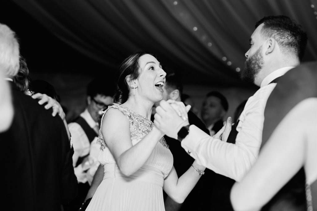 Black and white photo of guests laughing on the dance floor