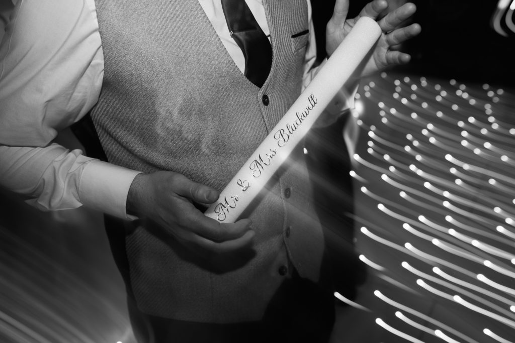Black and white close-up of a guest holding a foam glow stick