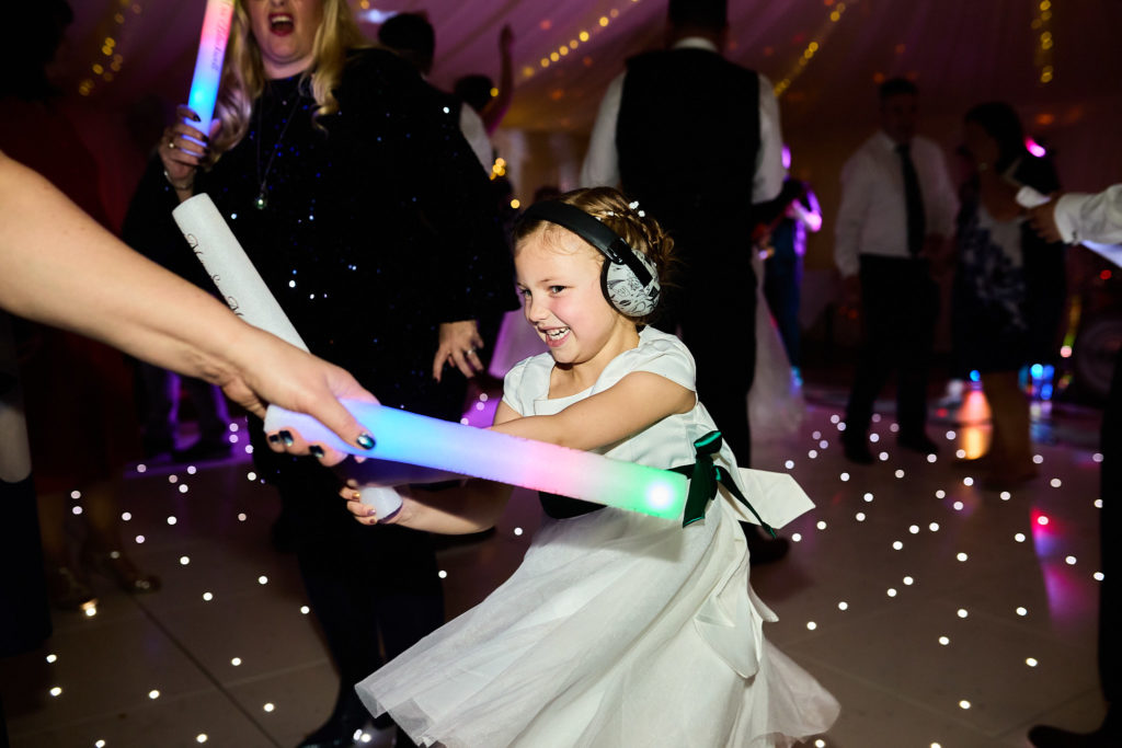 Young bridesmaid dancing with glow sticks on the dance floor