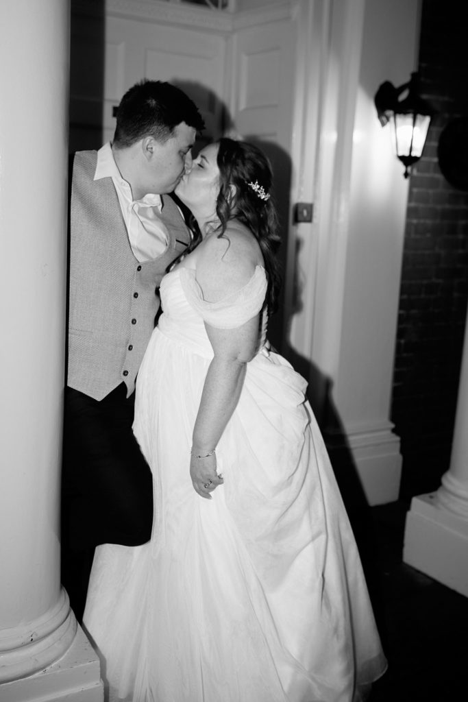 Black and white photo of the bride and groom kissing in the doorway at Mulberry House at night