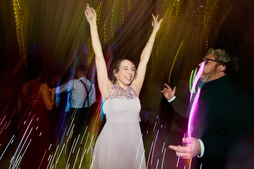 Wedding guest dancing with her arms in the air among streaks of light
