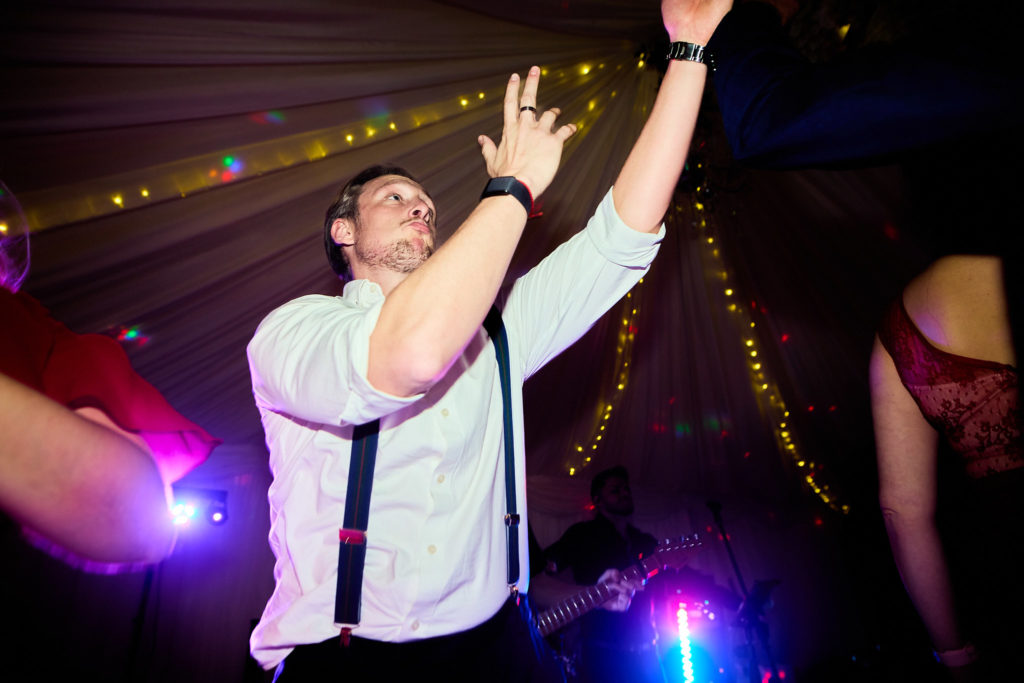Man in braces dancing with his arm in the air