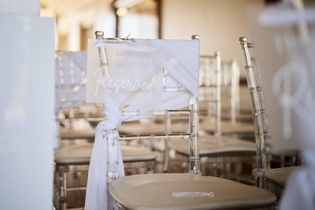 White ceremony chairs dressed with fabric sashes