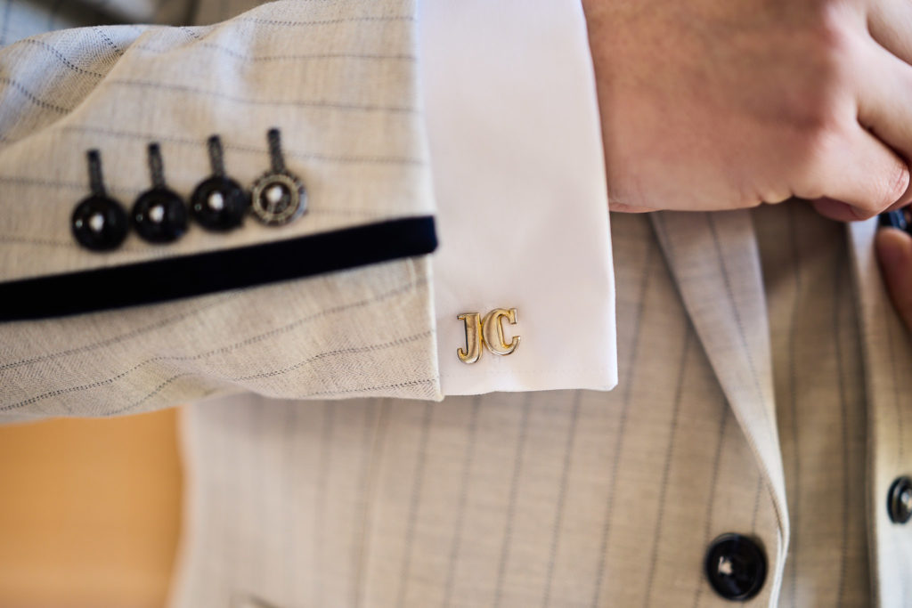 Close-up of the groom's cufflink and cream pinstripe suit sleeve