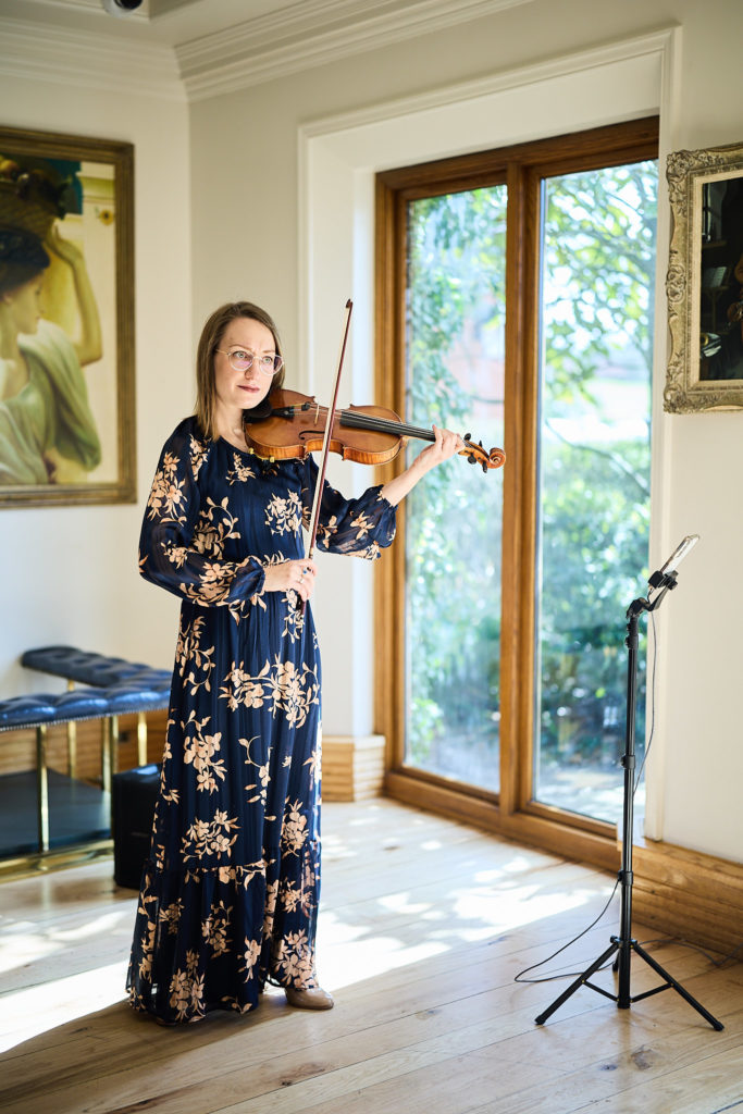 Violinist playing beside a window before the wedding ceremony
