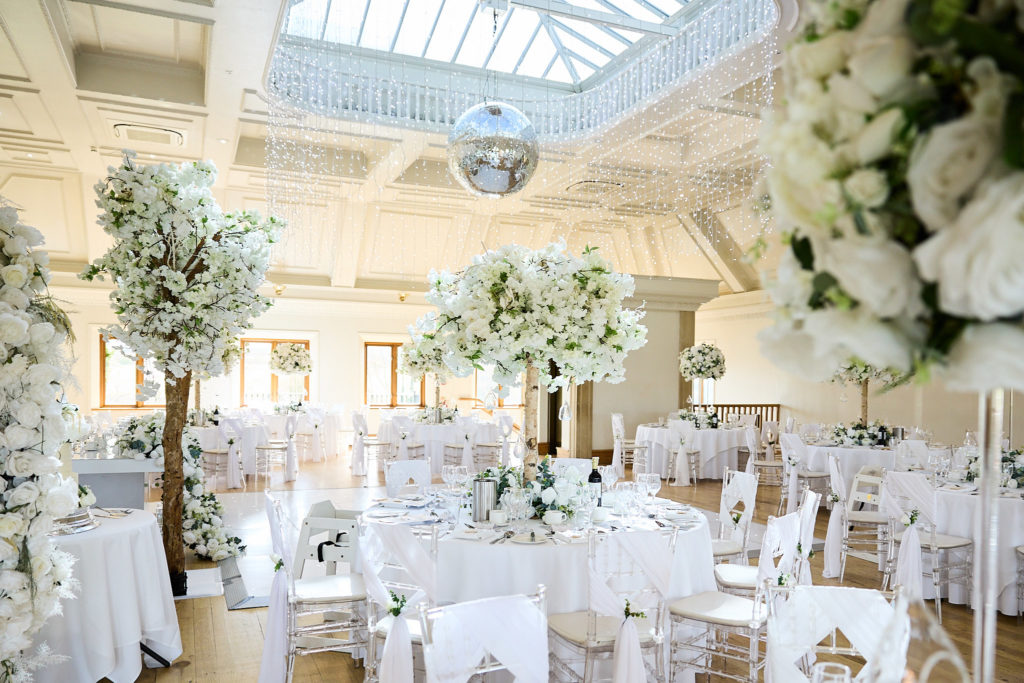 Reception room dressed with white flowers and blossom trees at Stock Brook Manor