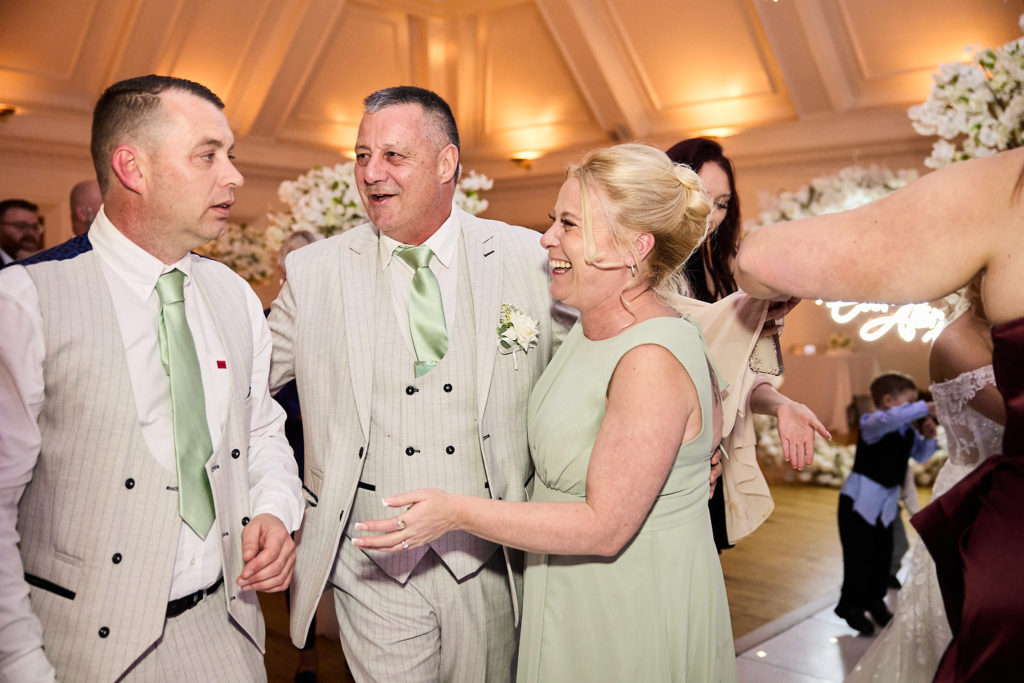 Groom laughing with an older couple at the reception