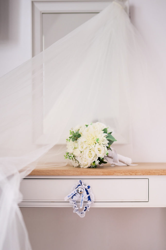 Bouquet of white roses on a dressing table beneath the hanging veil