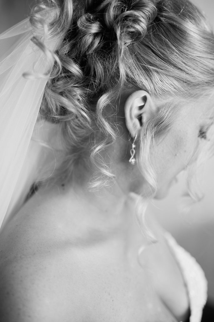 Black and white close-up of the bride's curled updo and earring