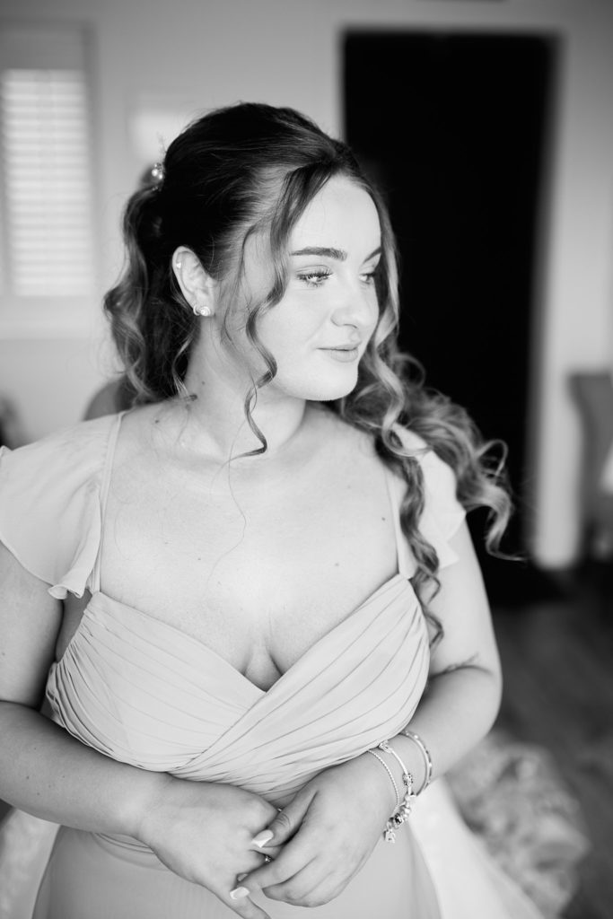 Black and white photo of a bridesmaid with curled hair looking down