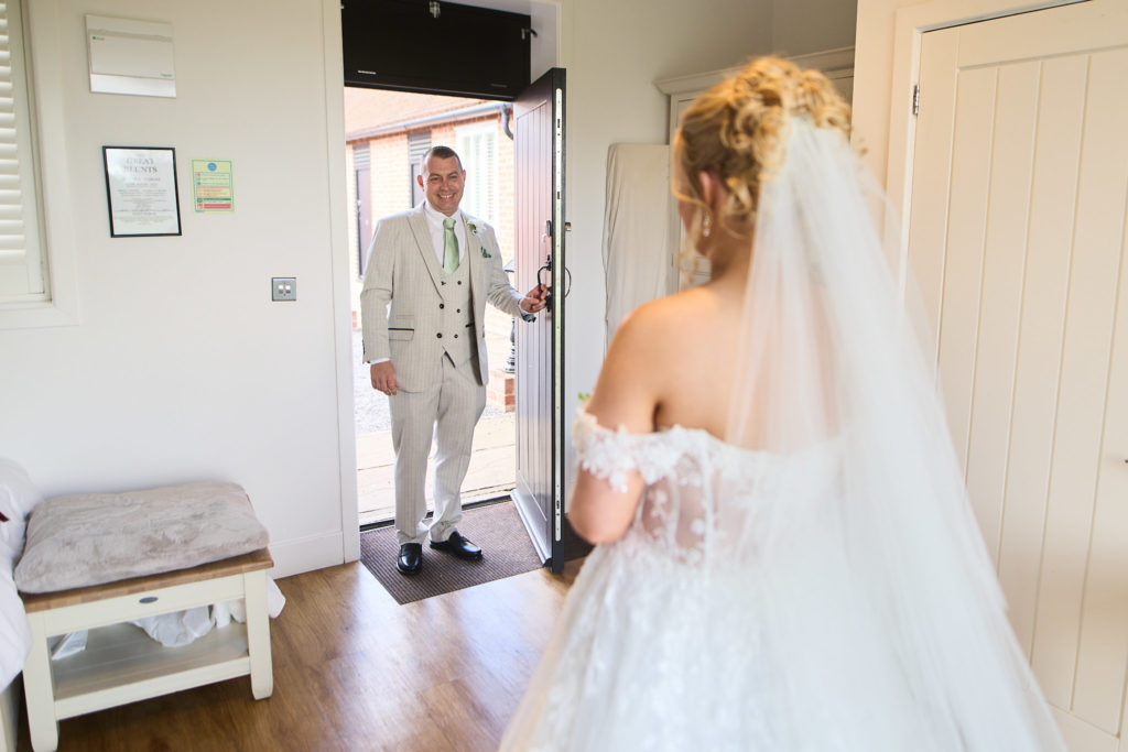 Man in a cream suit seeing the bride in her wedding dress for the first time
