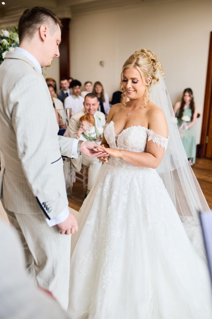 Bride smiling as the wedding ring is placed on her finger