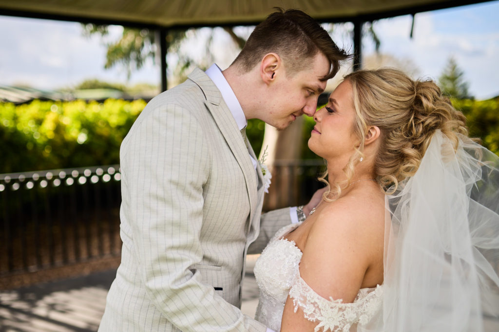 Bride and groom forehead to forehead in the bandstand at Stock Brook Manor