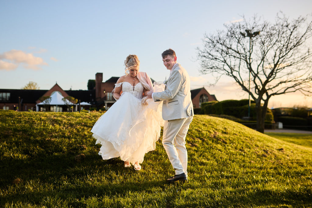 Bride and groom dancing on the grass at golden hour in front of Stock Brook Manor