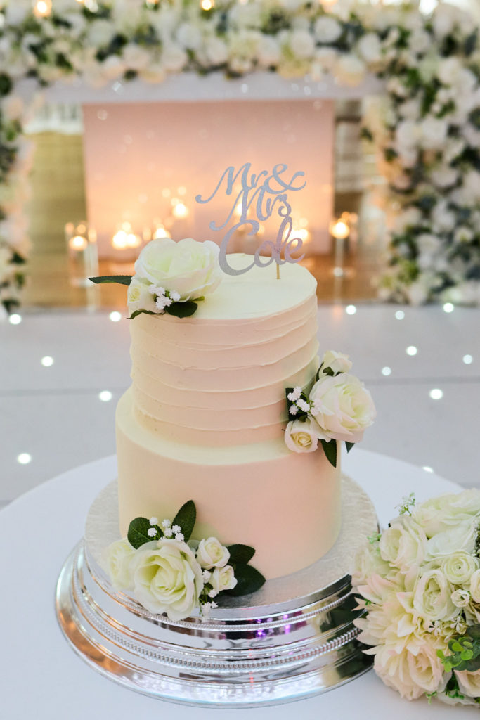 Two-tier wedding cake with white roses and a Mr and Mrs topper