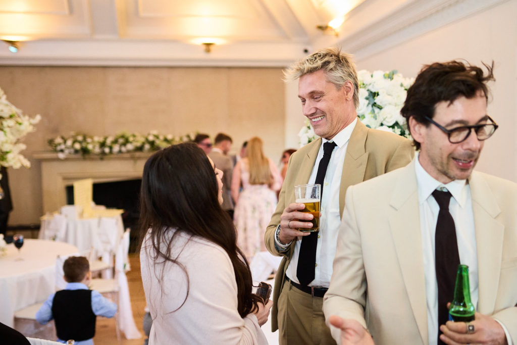 Wedding guests laughing with drinks at the reception