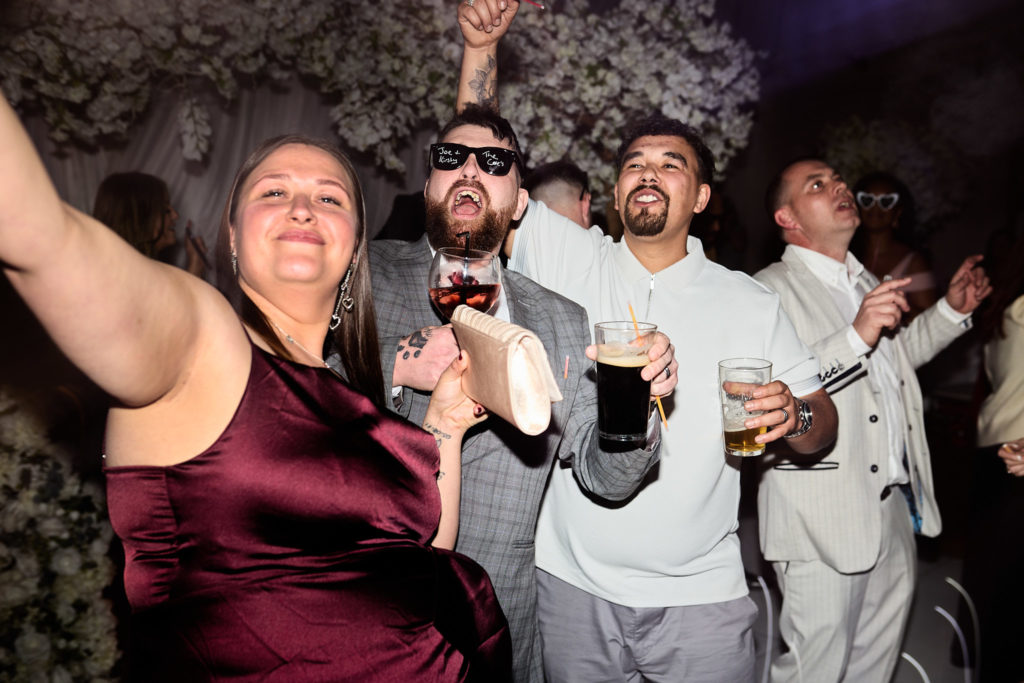 Wedding guests dancing, a woman in a burgundy dress with her arm raised