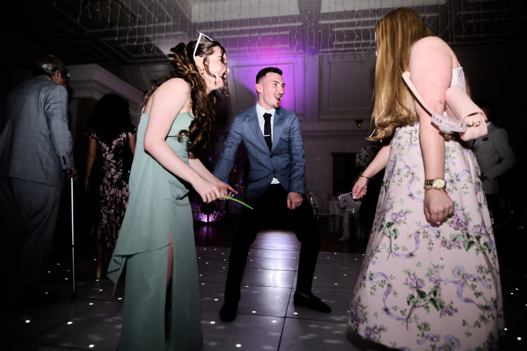 Wedding guests dancing with a bridesmaid in a sage green dress