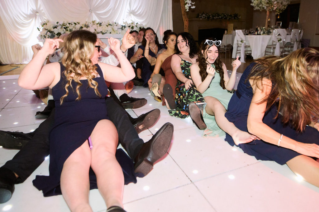 Wedding guests sitting in a row on the dance floor, laughing