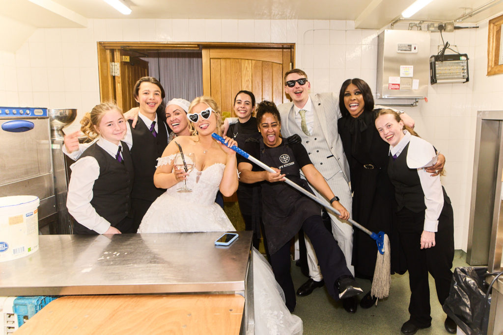 Bride posing with a group of staff in the venue kitchen
