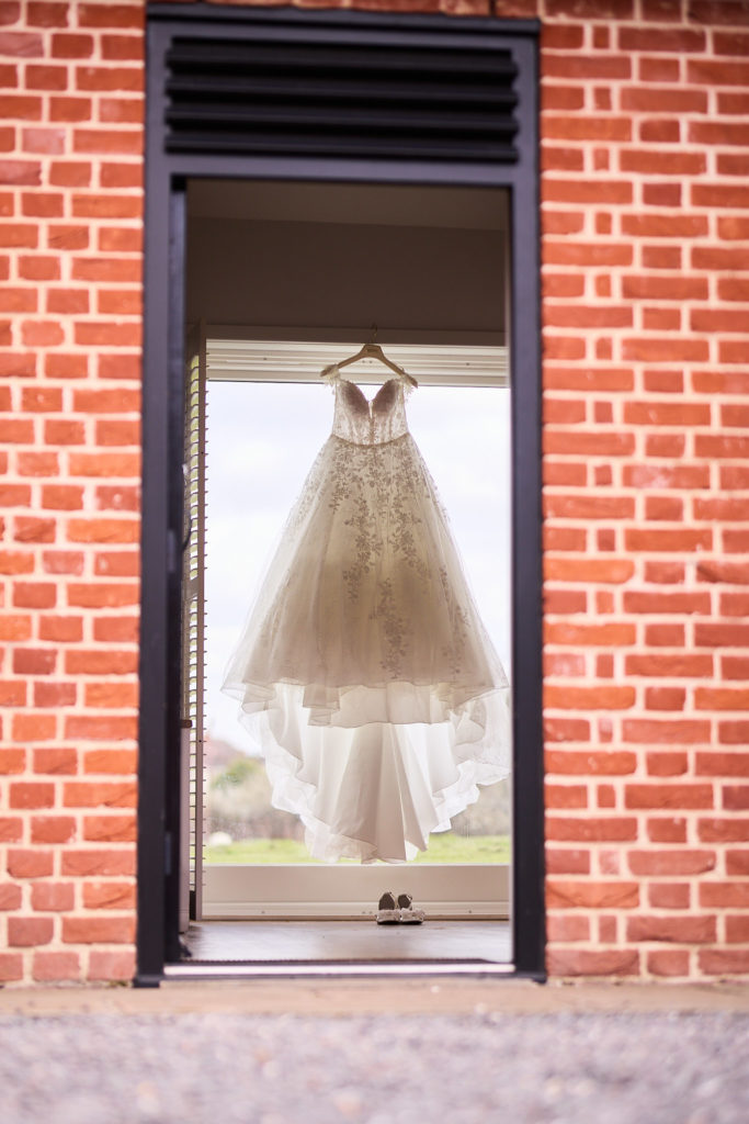 Wedding dress hanging in the window of a red-brick building