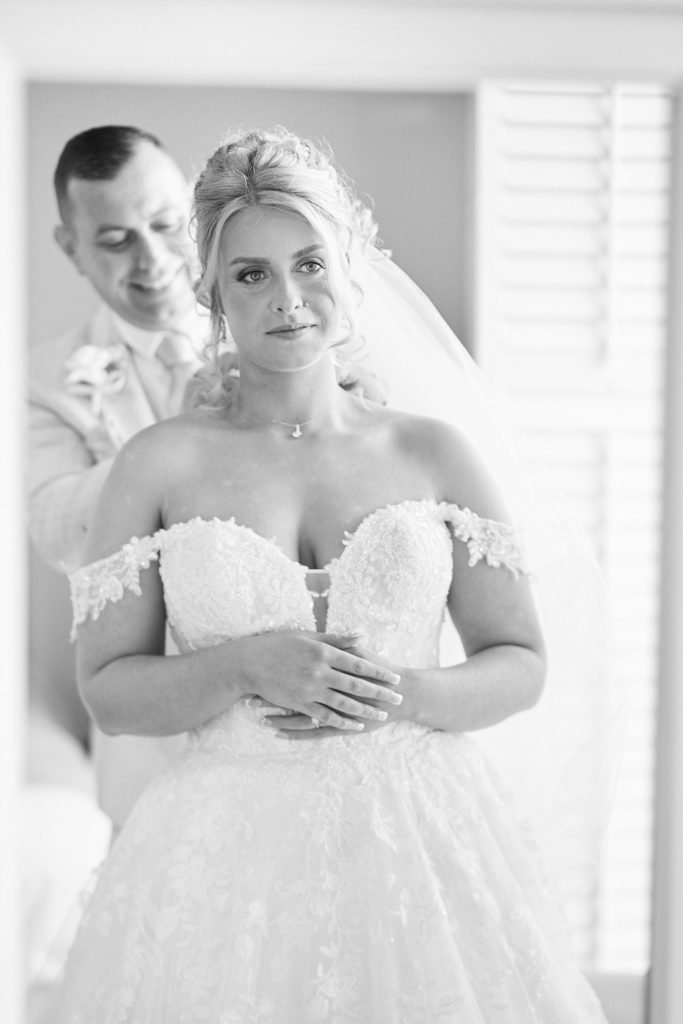 Black and white photo of the groom embracing the bride from behind