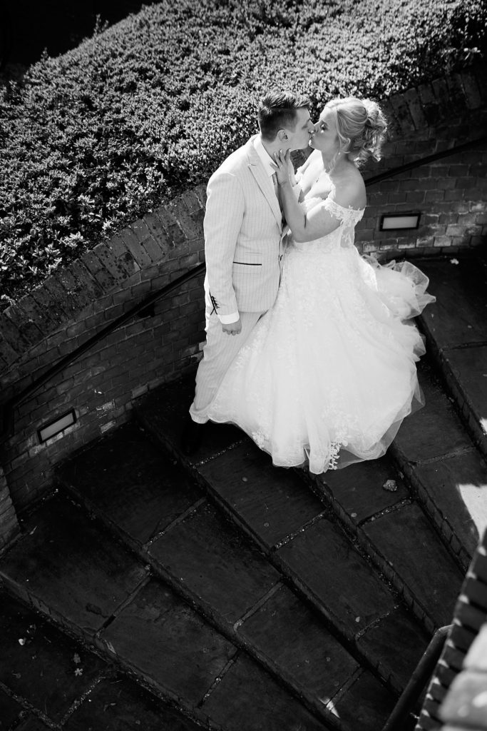 Black and white photo from above of the bride and groom kissing at Stock Brook Manor