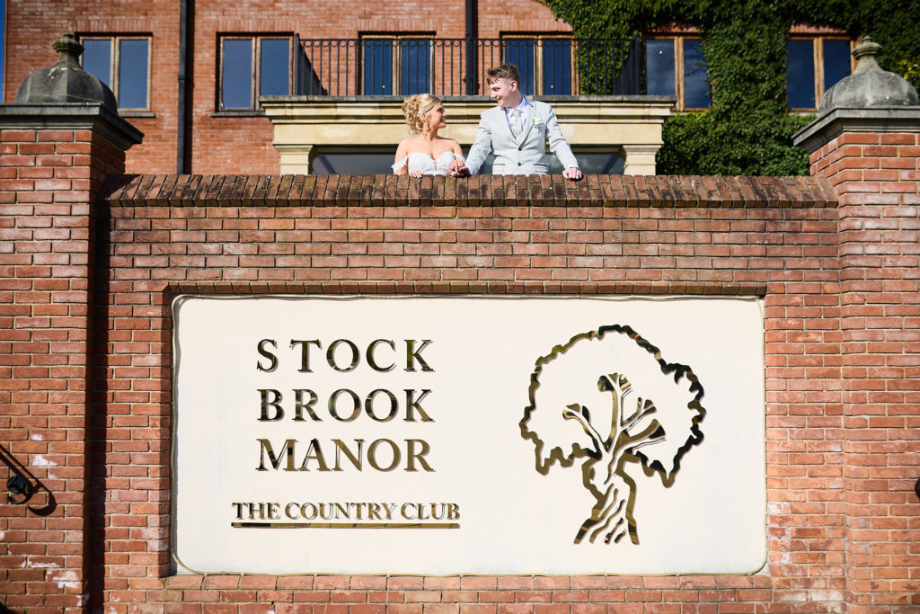 Stock Brook Manor sign on a brick wall with the bride and groom standing above it