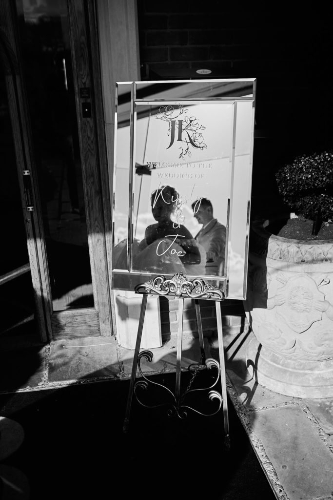 Black and white photo of the wedding welcome sign on an easel