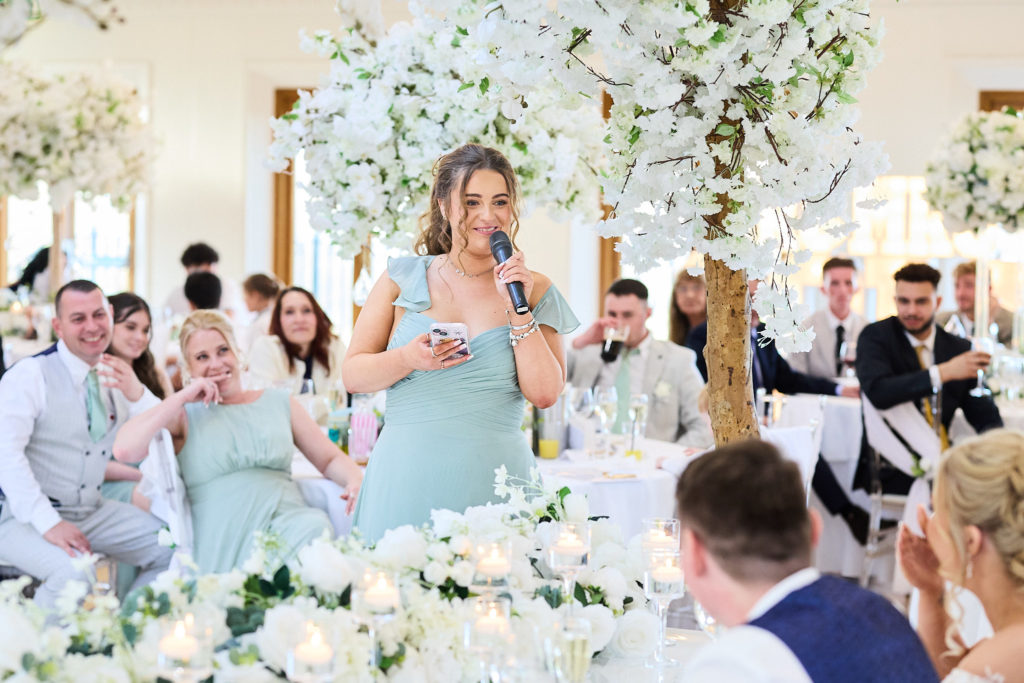 Bridesmaid giving a speech with a microphone as guests listen