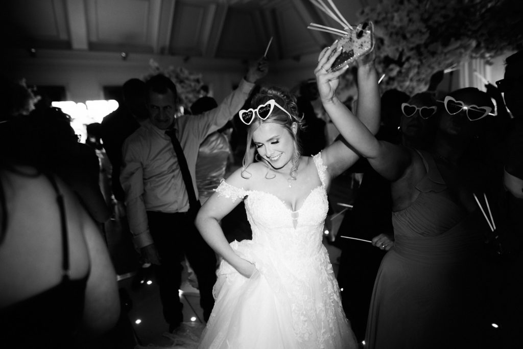 Black and white photo of the bride dancing in sunglasses