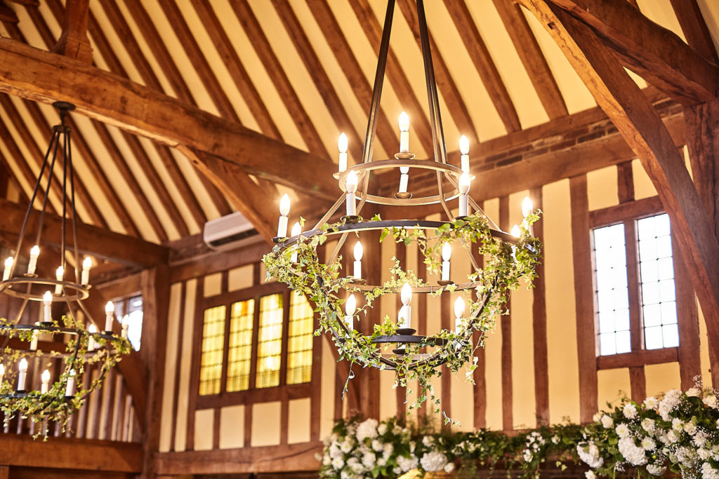 Iron chandeliers dressed with foliage in the timber-framed hall