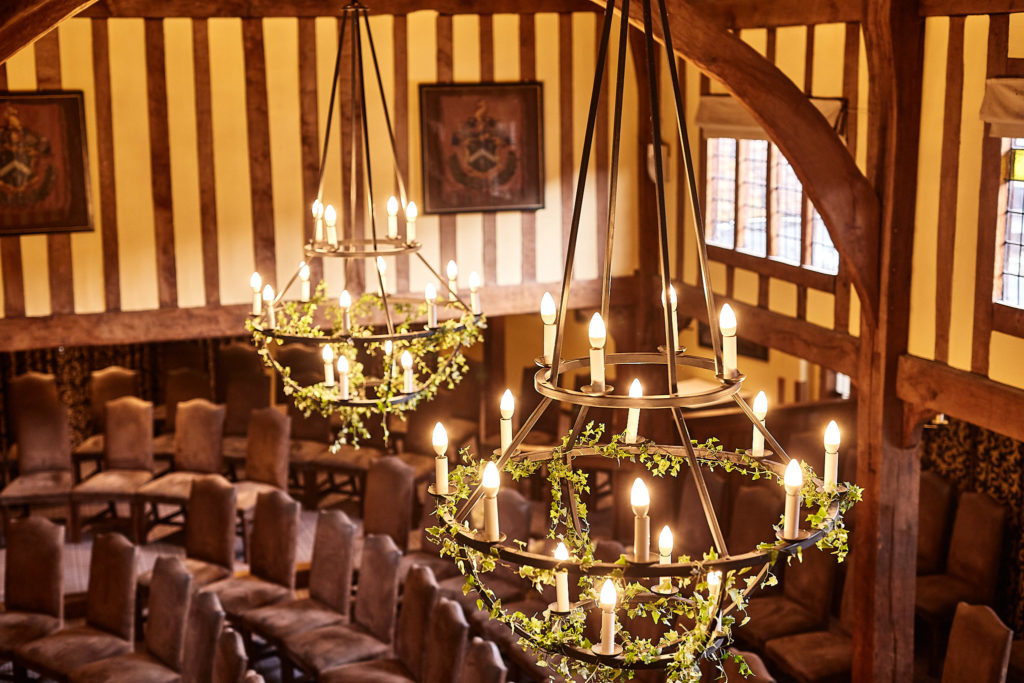 Ceremony chairs beneath foliage-wrapped chandeliers at The Swan at Lavenham