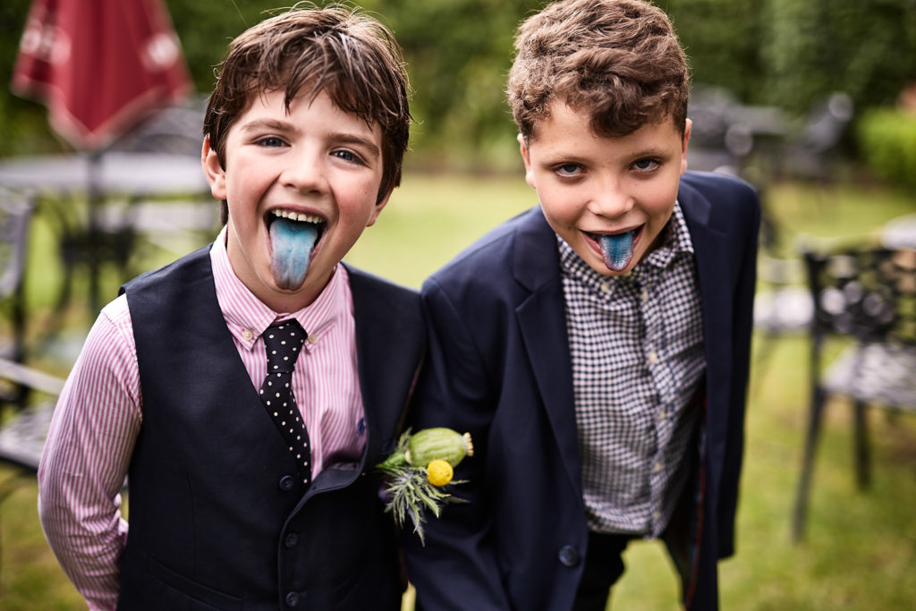 Two young page boys sticking out their blue tongues