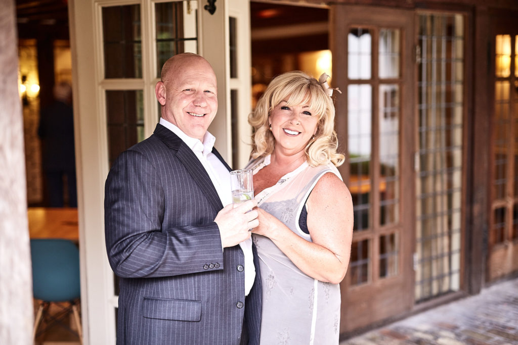 Couple smiling together outside the leaded windows at The Swan at Lavenham