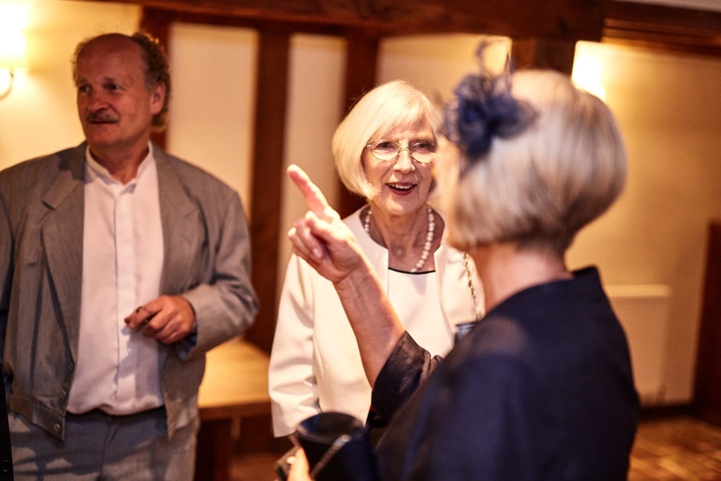 Wedding guests chatting before the ceremony, one in a navy fascinator