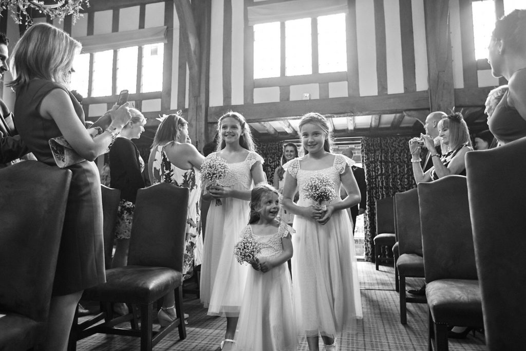 Black and white photo of flower girls in white dresses walking down the aisle