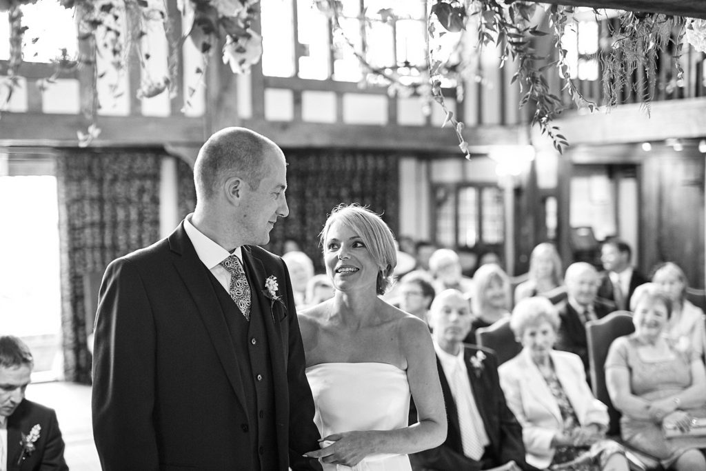 Black and white photo of the bride and groom standing together as guests look on
