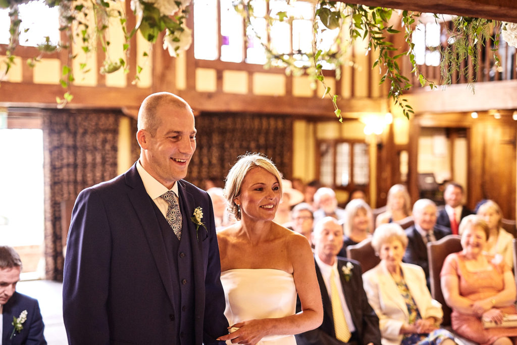 Bride and groom smiling at the start of their wedding ceremony at The Swan at Lavenham, Suffolk