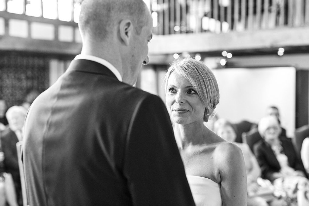 Black and white photo of the bride and groom facing each other during their vows
