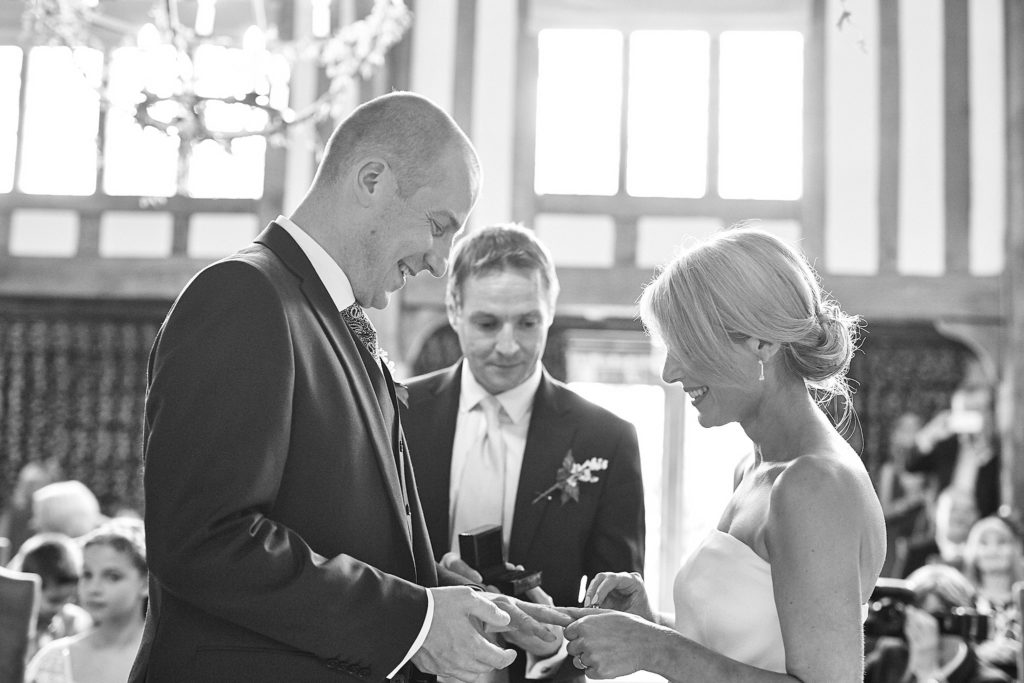 Black and white photo of the best man handing the rings to the groom