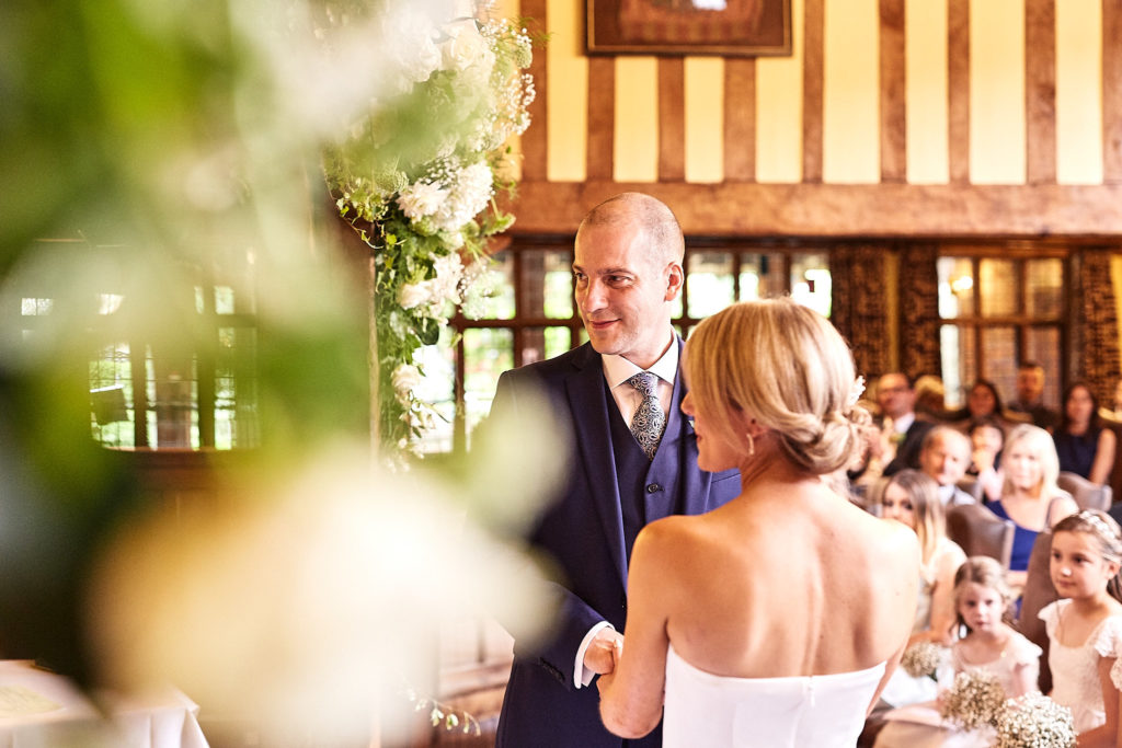 Bride and groom during their vows, seen through the ceremony flowers