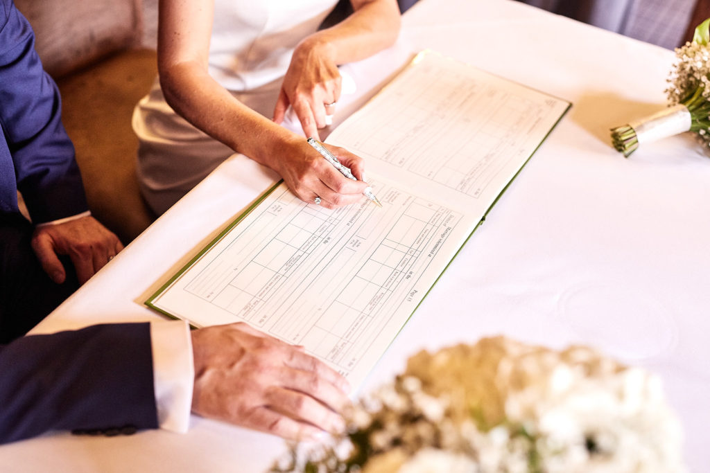 Close-up of hands signing the marriage register