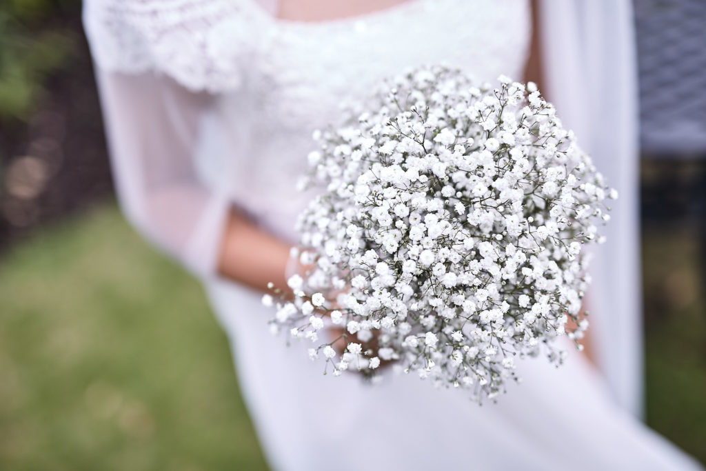Close-up of a gypsophila posy held against a white dress