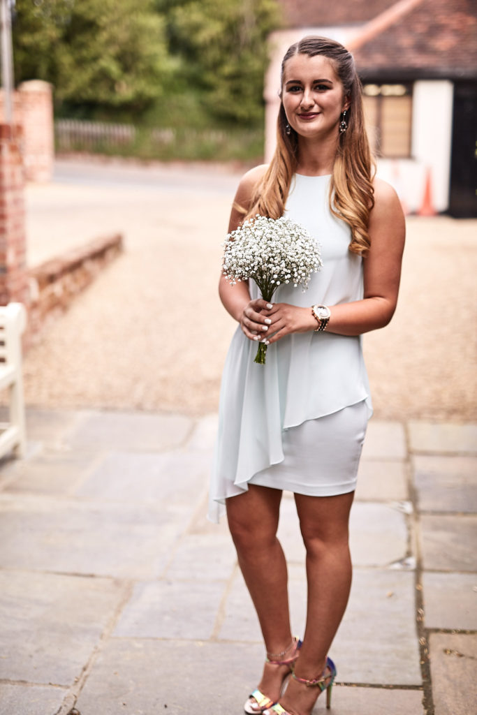Bridesmaid in a pale dress smiling with a gypsophila posy