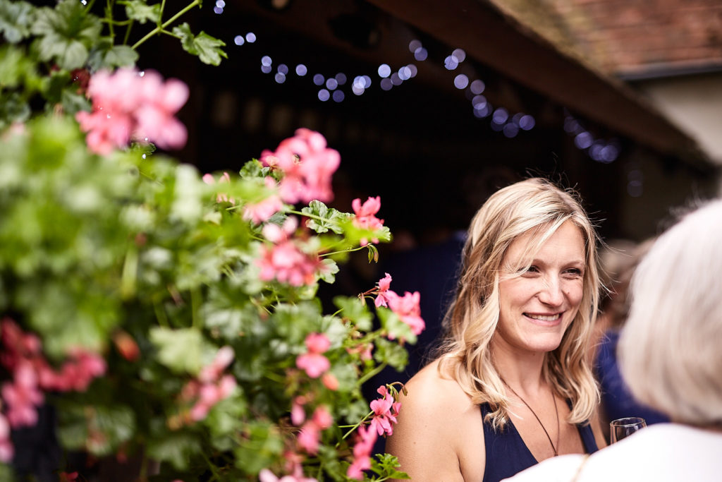 Wedding guest smiling beside a tub of pink geraniums