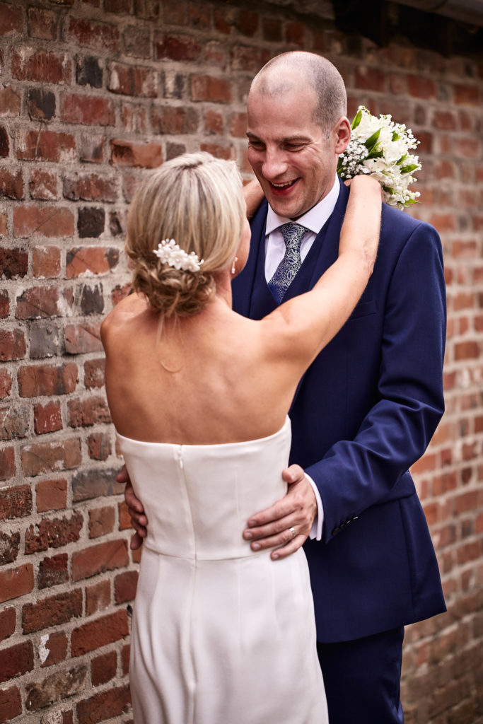 Bride with her arms round the groom's neck, holding her bouquet, in Lavenham