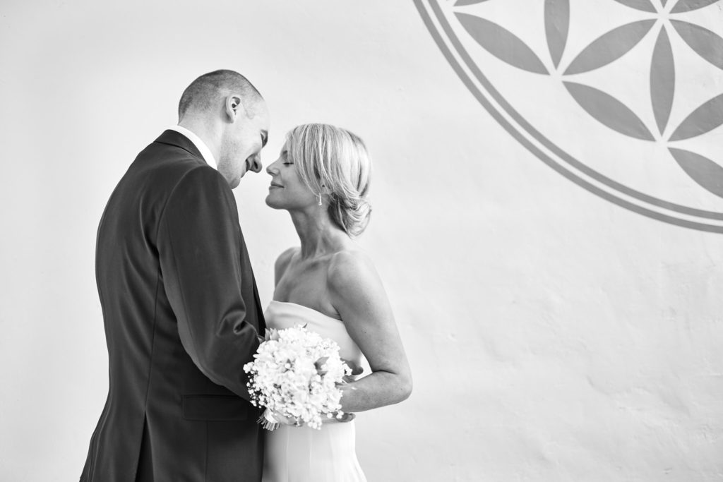Black and white photo of the bride and groom forehead to forehead beside a pargeted wall in Lavenham