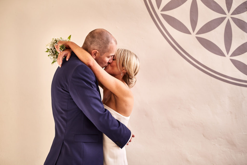 Bride and groom hugging beside a pargeted plaster wall in Lavenham