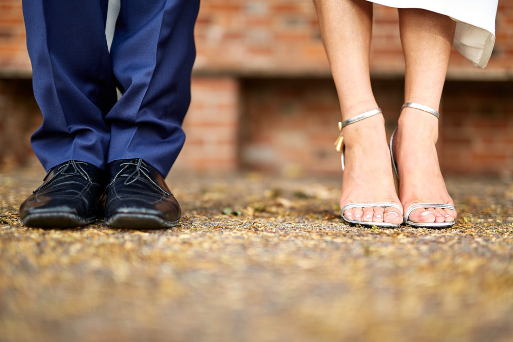 Close-up of the bride's and groom's feet side by side on a gravel path